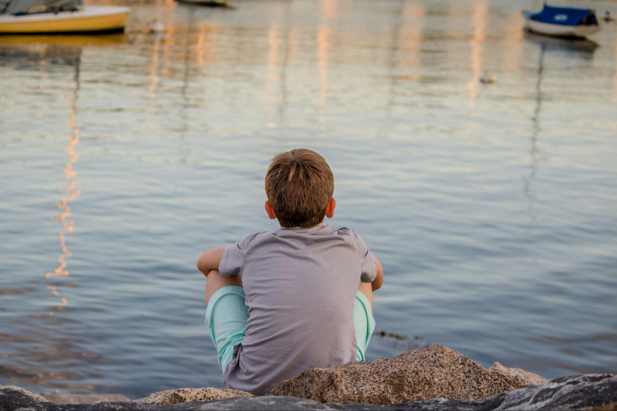 A young boy displaying signs of trauma, illustrating the impact of childhood trauma and the crucial role of a trauma coach in facilitating effective childhood trauma recovery.